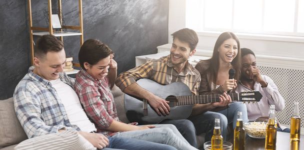 Домашняя вечеринка. Друзья играют на гитаре, поют караоке и веселятся
 - Фото, изображение