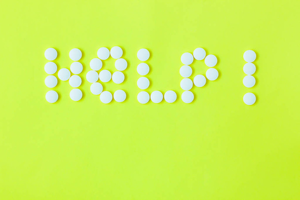 Pills in a shape of a word Help on a yellow background. Flat lay, top view, minimalistic style. - Photo, Image