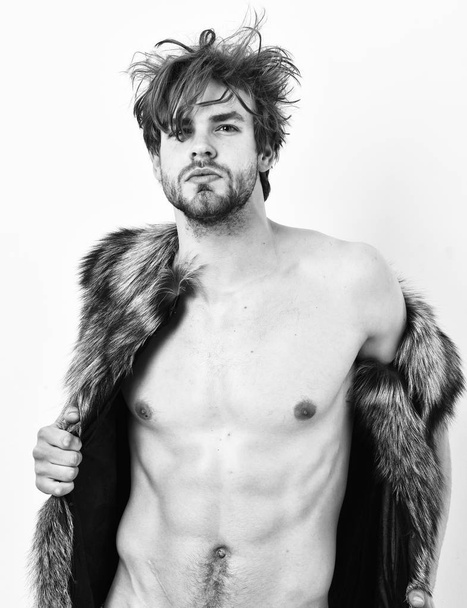 Guy attractive fashion model posing fur coat on naked body. Fashion concept. Richness and luxury lifestyle. Sexy sleepy rich macho tousled hair fur vest on white background. Fashion and pathos - Foto, Bild