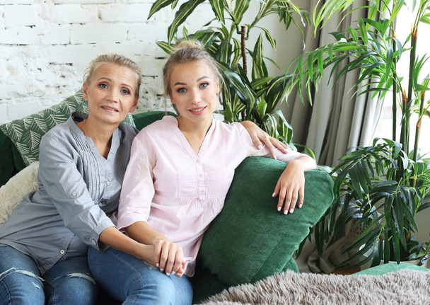 Beautiful senior mom and her adult daughter are hugging, looking at camera and smiling. At Home. - Foto, Bild
