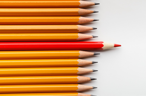 Red pencil standing between classic ones on white background - Photo, Image