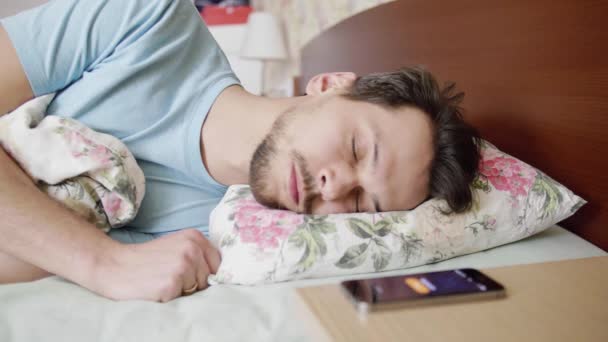 Homem com cabelo escuro dormindo na cama com travesseiro confortável, acorda quando o telefone toca
. - Filmagem, Vídeo