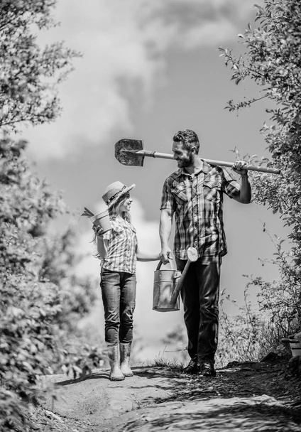 kid worker with dad hold box. family bonding. spring country side village. father and daughter on rancho. summer farming. farmer man with little girl. Working with plants. shovel and watering can - Fotoğraf, Görsel