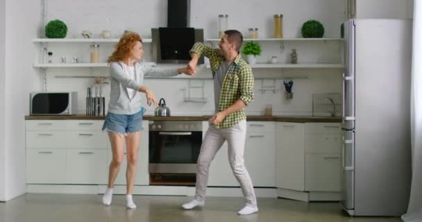 Happy man and woman are dancing in the morning in their kitchen - Filmati, video