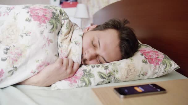 Ο άνθρωπος κοιμάται στο κρεβάτι με άνετο μαξιλάρι και κουβέρτα, δαχτυλίδια τηλεφώνου και ξυπνάει. - Πλάνα, βίντεο