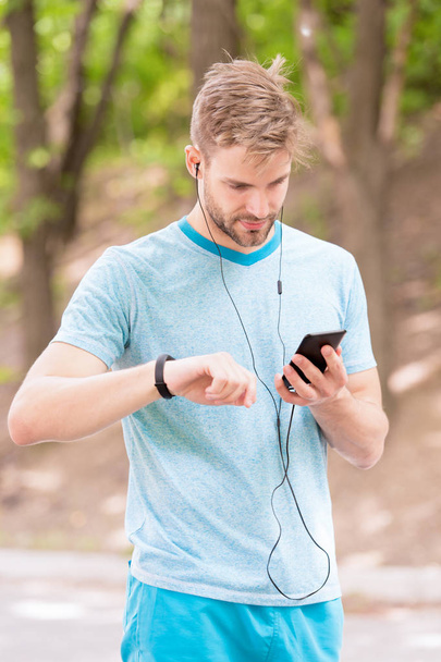Monitoring and boosting his training. Sportsman tracking his training with fitbit and smartphone. Fit man paring smartwatch with mobile device for training. Physical training and sports - Foto, Imagen