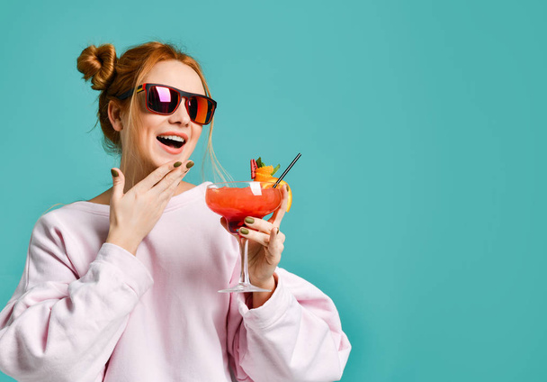 Joyful clubbing young woman with tropic cocktail strawberry margarita chat with friends and laughs during party - Фото, зображення