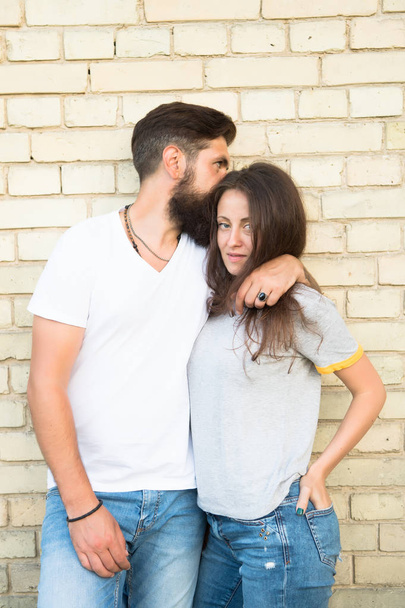 We are just a couple in love with each other. Loving couple hugging on brick wall. Family couple of bearded man and sexy woman. Sensual couple in casual style - Foto, Bild