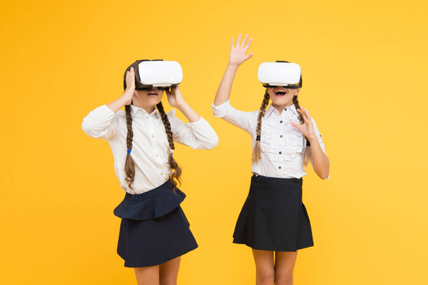 Yeni deneyimlerin tadını çıkar. Mutlu çocuklar modern teknolojiyi kullanır. Gelecekteki eğitim. Okula dönüyorum. Dijital gelecek ve yenilik. Sanal gerçeklik. VR kulaklıklı küçük kızlar. Çocuklar kablosuz VR gözlük takıyor - Fotoğraf, Görsel