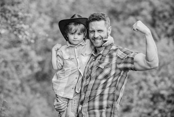 Rustic family. Growing cute cowboy. Small helper in garden. Little boy and father in nature background. Spirit of adventures. Strong like father. Power being father. Child having fun cowboy dad - Фото, изображение