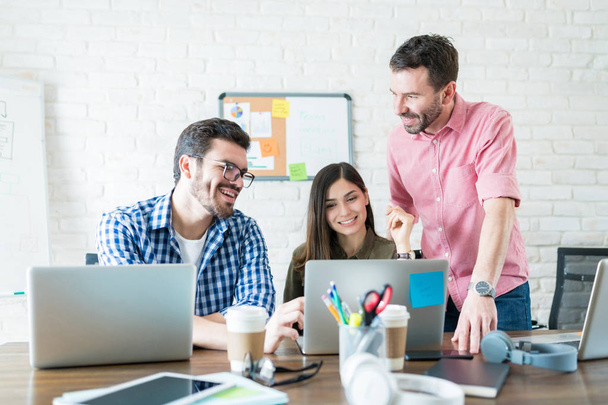 Homens e mulheres empresários que se comunicam através de laptop em reunião no local de trabalho
 - Foto, Imagem