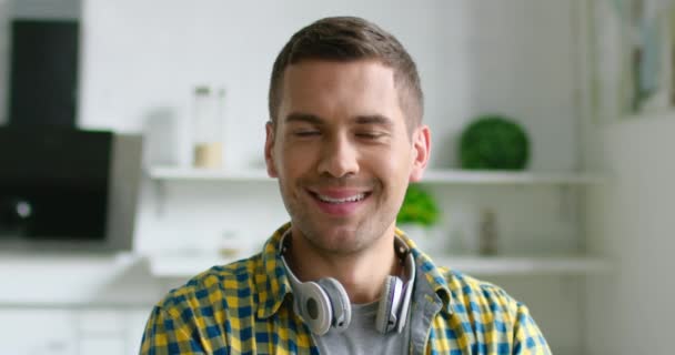 Retrato do jovem homem feliz usando fone de ouvido sem fio em seu pescoço
 - Filmagem, Vídeo