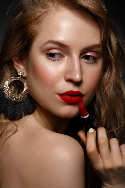 Beautiful girl with red lips and classic makeup and curls with lipstick in hand. Beauty face. - Foto, Imagem