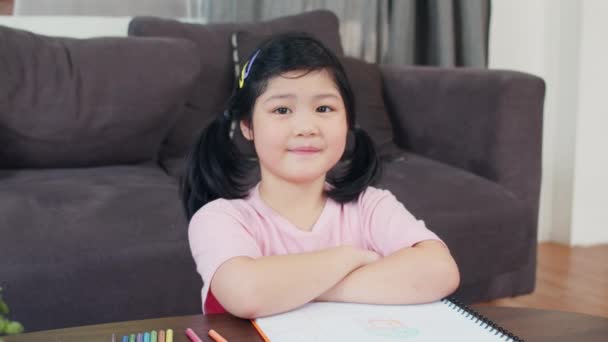 Portrétní Asijská dívka se spokojeně usmívá doma. Mladá japonská dívka odpočívá v obýváku a dívá se na kameru, zatímco v obývacím pokoji u domu se dopolední představa ležela. Zpomaleně. - Záběry, video