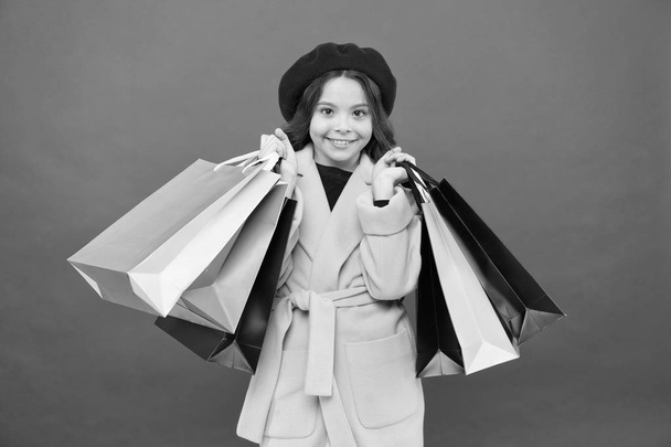 Girl cute kid hold shopping bags red background. Get discount shopping on birthday holiday. Fashionista adore shopping. Obsessed with shopping. Get major wardrobe refresh with spring sales at stores - 写真・画像