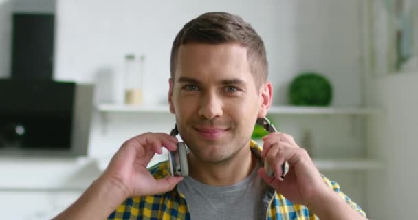 Retrato de jovem homem feliz colocando fone de ouvido sem fio em
 - Filmagem, Vídeo