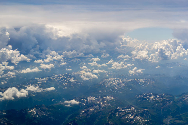 The bird's eye view on the sky with the huge fluffy dramatic clouds above the Alps. - Photo, Image