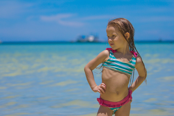 Красивая маленькая девочка, стоящая в воде на пляже
 - Фото, изображение