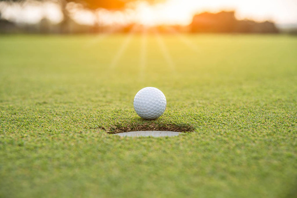 Bola de golfe colocando na grama verde perto de golfe buraco
  - Foto, Imagem