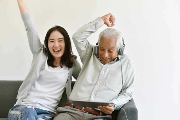 Счастливое семейное время, улыбающаяся азиатская дочь и пожилой отец наслаждаться просмотром фильма с планшетного компьютера вместе, пожилых людей и социальных медиа концепции образа жизни
. - Фото, изображение