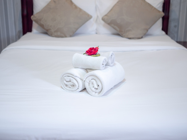Białe ręczniki dekoracji z czerwonym kwiatem na białym czystym łóżku w Ho - Zdjęcie, obraz