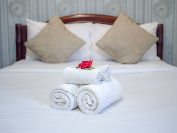 Λευκές πετσέτες διακόσμηση με κόκκινο λουλούδι σε λευκό καθαρό κρεβάτι σε Ho - Φωτογραφία, εικόνα