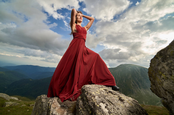 Beautiful female fashion model in red dress on mountain rocks - Photo, Image