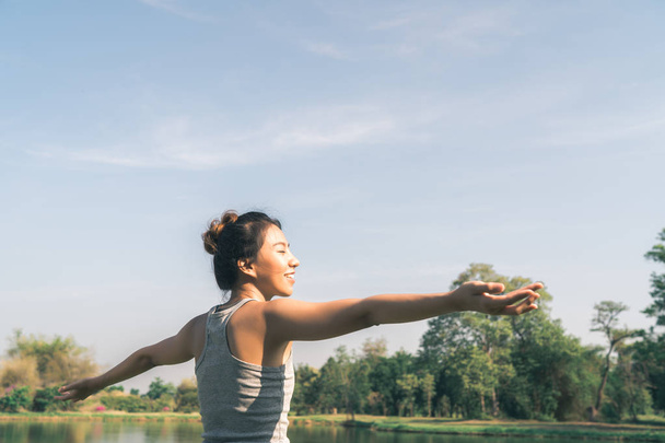 若いアジア女性ヨガは屋外、冷静を保ち、内側の平和を探求するヨガを練習しながら瞑想します。ヨガでは、公園で湖の近くの健康のため良い利点があります。スポーツと健康的なライフ スタイルのコンセプト. - 写真・画像