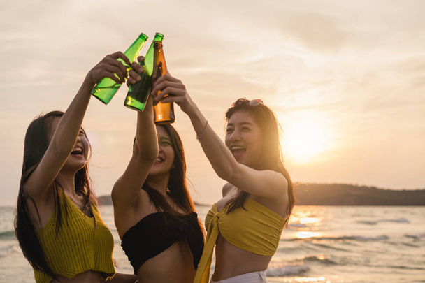 Gruppe asiatischer Teenagermädchen, die am Strand feiern, Freunde, die gerne Bier am Strand trinken, wenn die Sonne untergeht. Outdoor-Aktivitäten Freunde reisen Urlaub Sommer-Konzept. - Foto, Bild