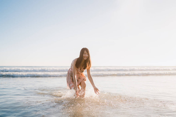Mujer asiática joven caminando en la playa. Hermosa mujer feliz relajarse caminando en la playa cerca del mar al atardecer en la noche. Estilo de vida de las mujeres viajan en concepto de playa
. - Foto, Imagen