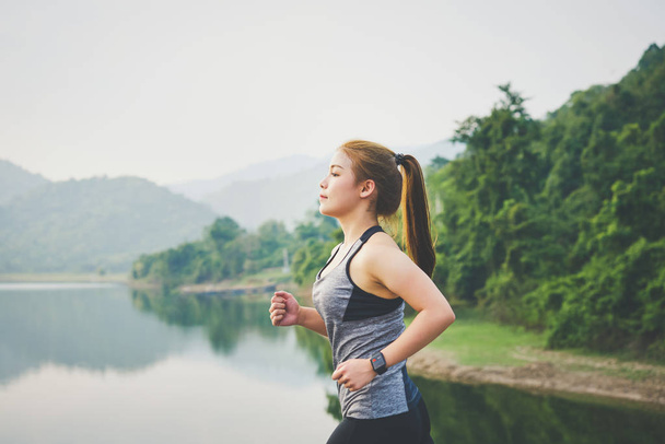 Jeune femme asiatique jogging courir dans le parc à l'air frais et porter montre de sport et de vérifier sa performance. technologie santé bien-être concept
. - Photo, image