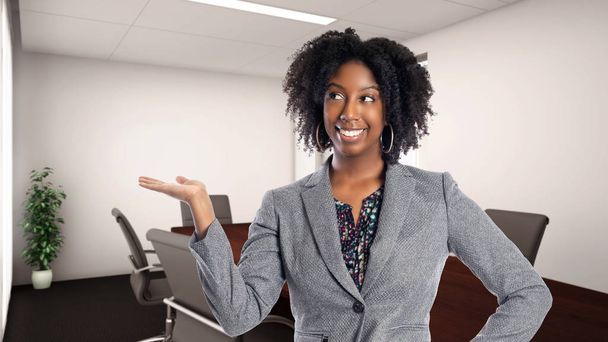 Black African American businesswoman in an office advertising or presenting something.  She is an owner or an executive of the workplace.  Depicts careers and startup business.  - Foto, afbeelding