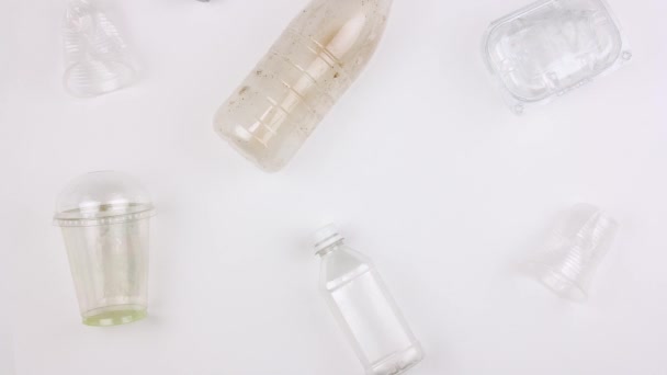 different used dirty plastic disposable tableware and garbage, bottles cups and containers moves on white background, seamless looping, stopmotion animation, big ecological pollution problem - Materiał filmowy, wideo