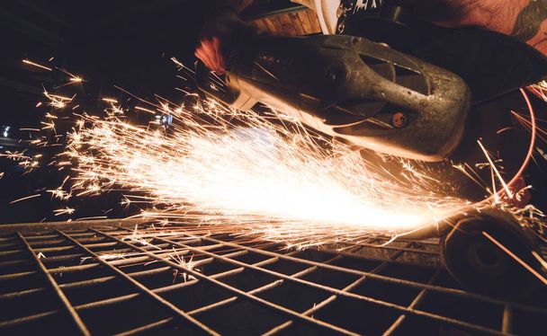 Worker Using Angle Grinder in Factory and throwing sparks. - Photo, image