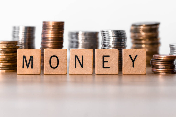"Geld "buchstabiert in Holzfliesen mit Münzen im Hintergrund - Foto, Bild