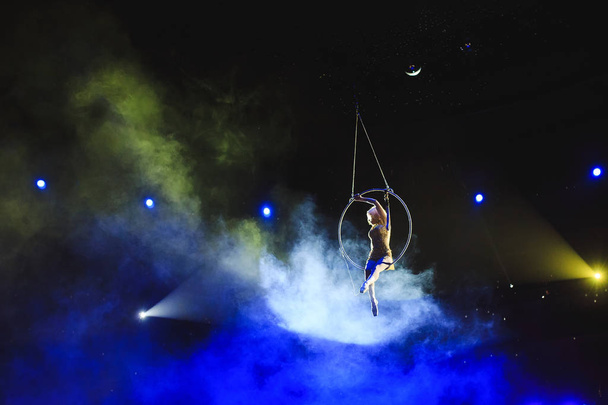 Aerial acrobat in the ring. A young girl performs the acrobatic elements in the air ring. - Foto, immagini