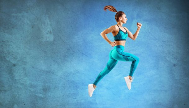 Молодая бегунья в бирюзовой спортивной одежде прыгает в воздух
. - Фото, изображение