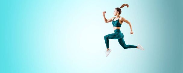 Jeune femme coureuse en bleu sportswear saut dans les airs
. - Photo, image
