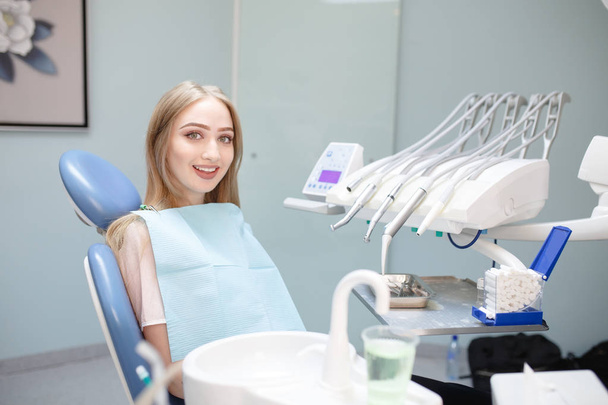 A happy patient in a dental clinic sits in a chair - Fotografie, Obrázek