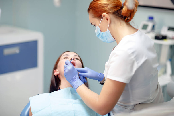female dentist checking patient girl teeth in a clinic - Fotoğraf, Görsel