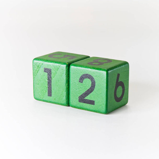 Número doze escrito em um cubo verde de madeira em fundo branco
 - Foto, Imagem