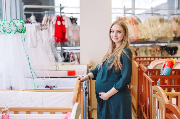 Pregnant girl chooses a baby cot in the store. - Valokuva, kuva