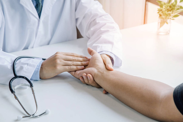 Dokter houdt handen vast en laat troostende raadgevers achter aan patiënt. - Foto, afbeelding
