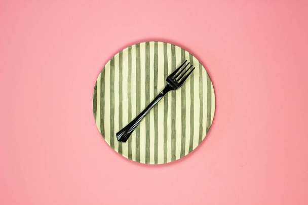 A plate and fork on a pink background. Minimalism. - Fotografie, Obrázek
