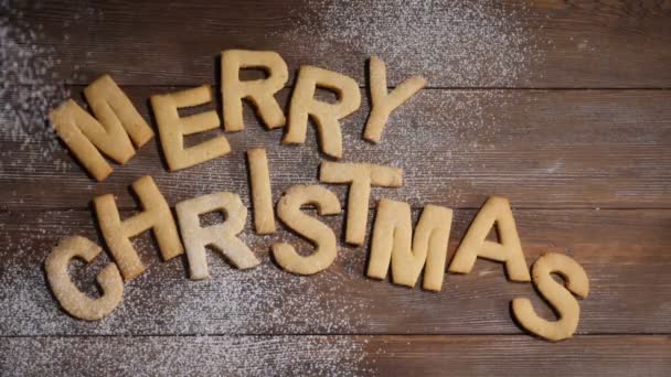 Happy New Year concept. Merry christmas note written with cookies letters on brown wooden background. White powder falling down in slow motion. hd - Footage, Video