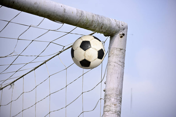 Anotando un gol, la pelota de fútbol tiende a entrar en el gol de fútbol
 - Foto, Imagen