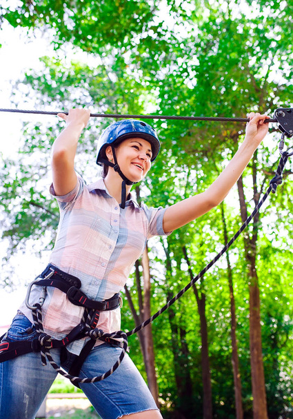 adventure climbing high wire park - people on course in mountain helmet and safety equipment - Foto, afbeelding
