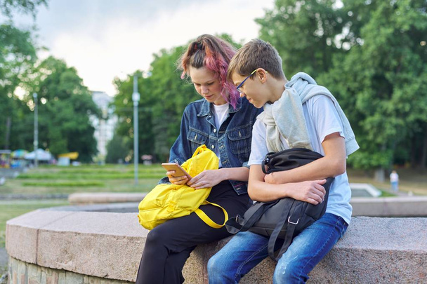 Retrato ao ar livre de dois adolescentes falantes com smartphone
 - Foto, Imagem