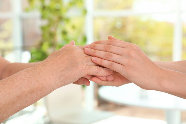 People holding hands together on blurred background, closeup. Help and elderly care concept - Photo, Image