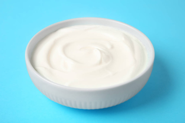 Bowl of sour cream on light blue background - Foto, Bild
